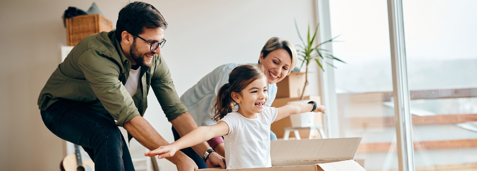 Gelukkige dochter die plezier heeft met haar ouders tijdens de verhuizing naar een nieuw huis